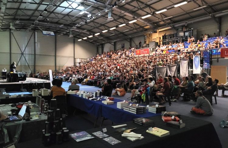 La salle comble lors d'une conférence au Festival d'astronomie, avec un stand d'ouvrages proposés à la vente