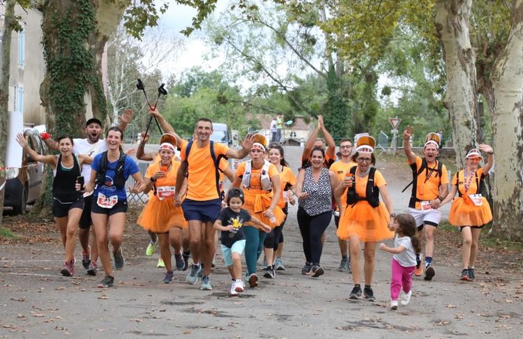 Des participants, hommes, femmes, enfants, déguisés en train de courir en levant les bras