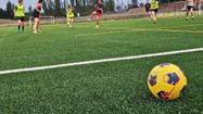 Une vue du terrain de foot synthétique en rafles de maïs, avec des joueuses en train de s'entraîner