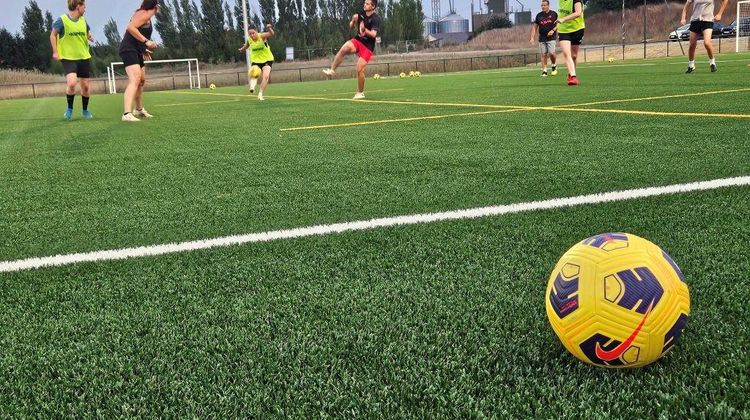 Une vue du terrain de foot synthétique en rafles de maïs, avec des joueuses en train de s'entraîner