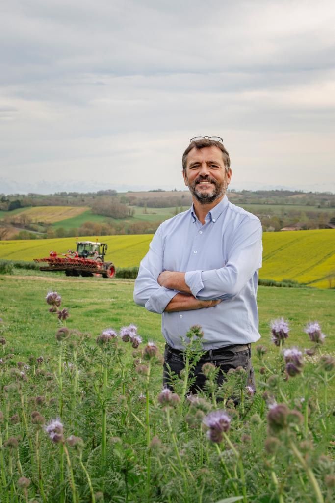 Michael Ehmann au milieu des champs avec une moissonneuse-batteuse à l'arrière plan