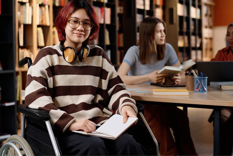 Une étudiante en situation de handicap étudie à la bibliothèque.