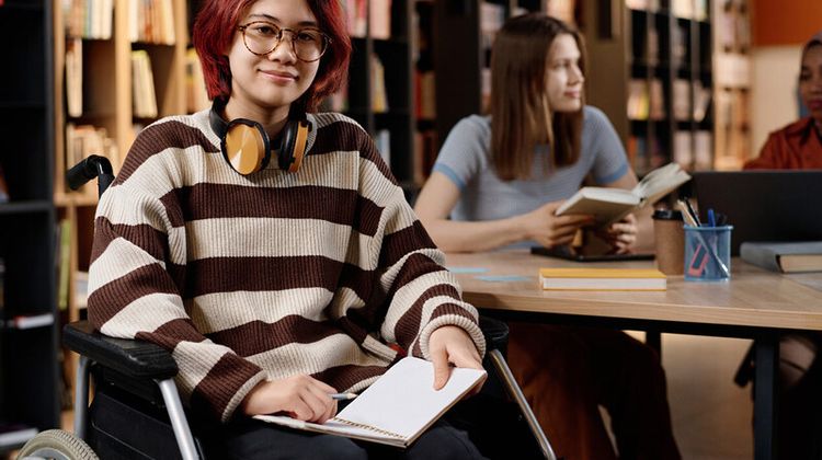 Une étudiante en situation de handicap étudie à la bibliothèque.