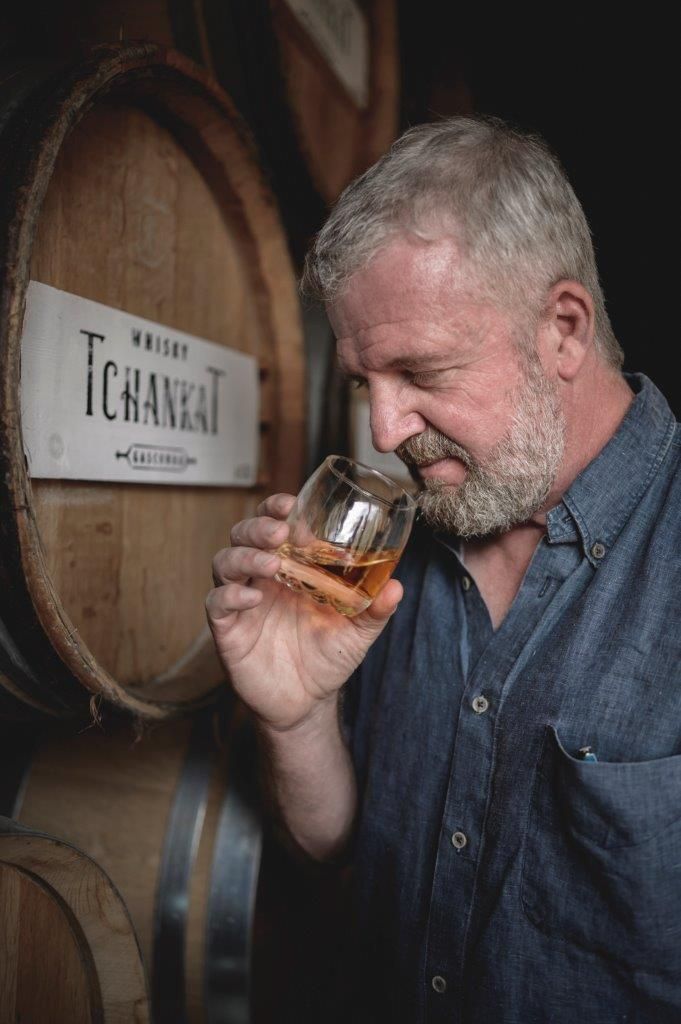 David Antajan en train de déguster un verre de Tchankat devant un tonneau dans le chai