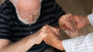 Un sénior essayant de se relever avec l'aide d'une autre personne.