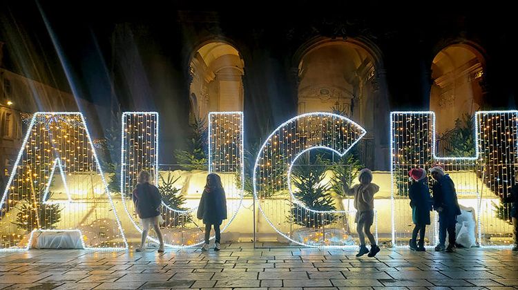 Des enfants la nuit devant des lettres géantes illuminées indiquant Auch, devant la cathédrale