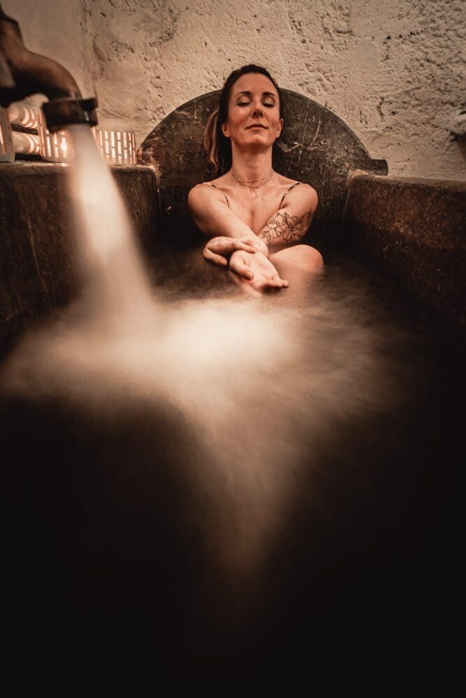 Des bains relaxants dans les baignoires historiques en marbre foncé, pour profiter des eaux férugineuses de l'espace de bien-être Les Bains de Secours.
